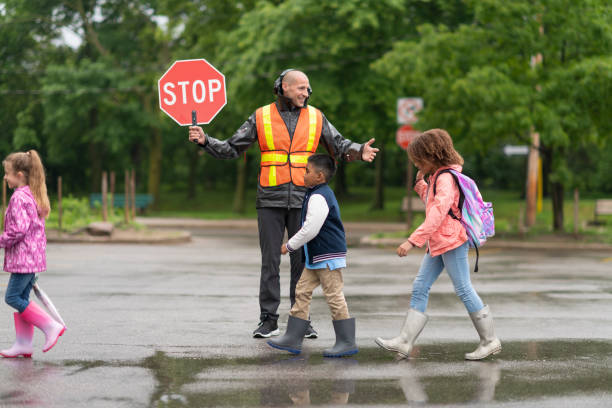 o protetor de sorriso do cruzamento ajuda estudantes com segurança atravessar a rua - crossing guard - fotografias e filmes do acervo