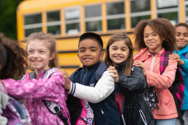 istock Diverse group of students standing outside school bus 1166892613
