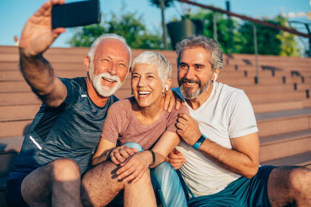Cheerful mature friends taking selfie after working out
