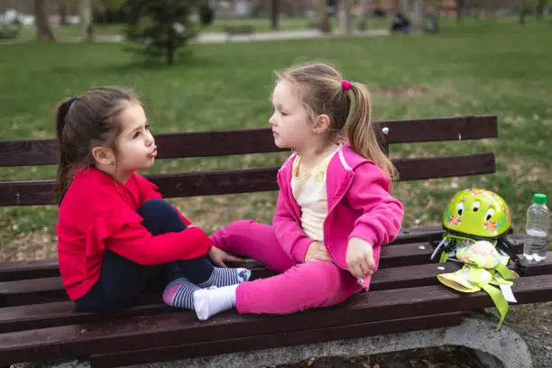 Photo of Cute children sitting on a bench and talking