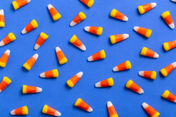Large group of Halloween candy corn on vibrant blue background.