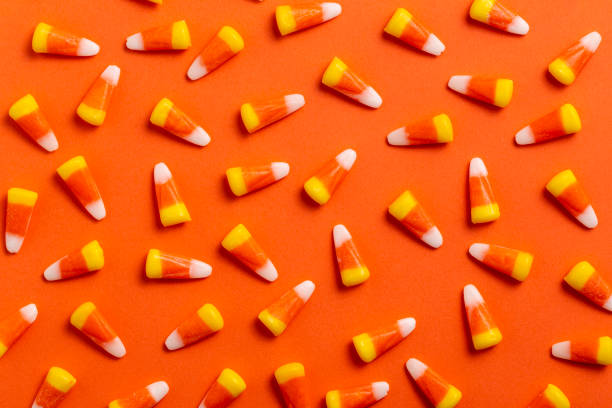 Halloween Candy Corn Blue Background Large group of Halloween candy corn on vibrant Orange background. candy corn stock pictures, royalty-free photos & images