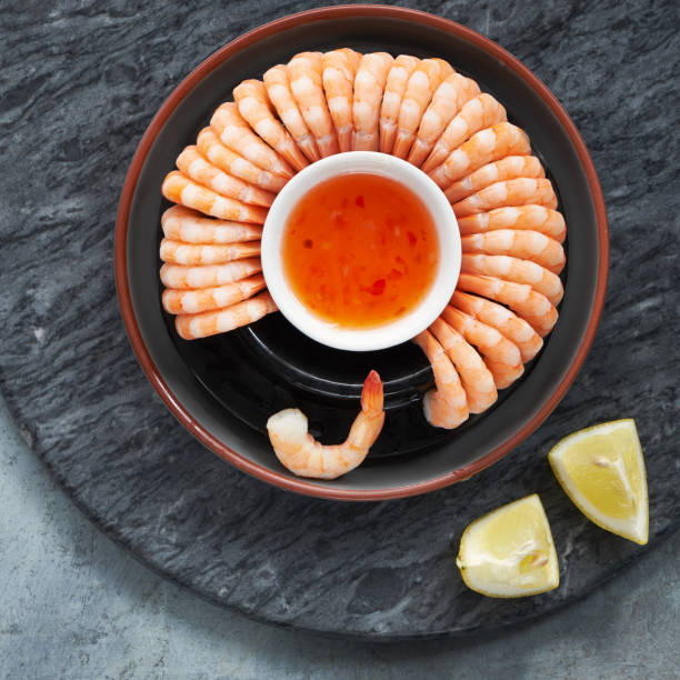 Zesty lemon and garlic prawns served on a dark plate with lemons