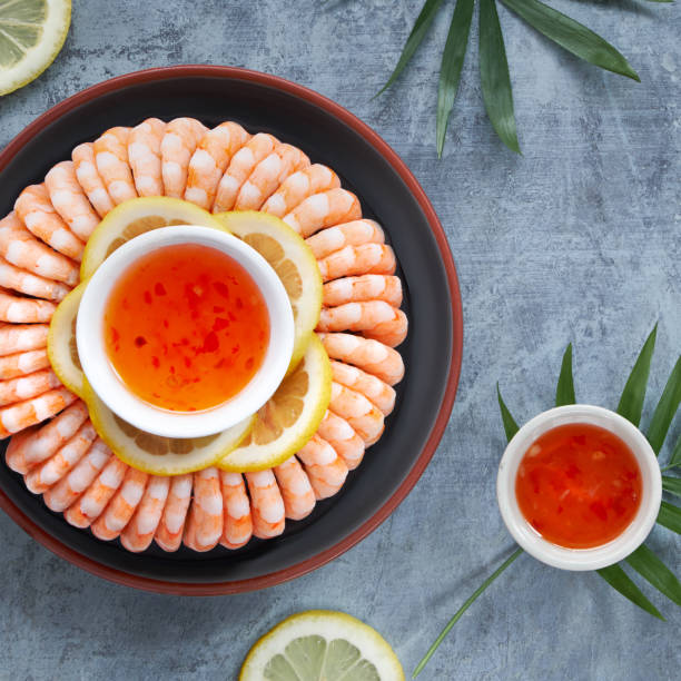 istock Zesty lemon and garlic prawns served on a dark plate with lemons 1166896275