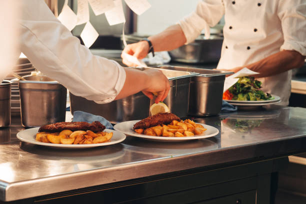istock Food orders on the kitchen table in the restaurant, chief decorating schnitzel and fried potatoes, traditional german plate 1166898612