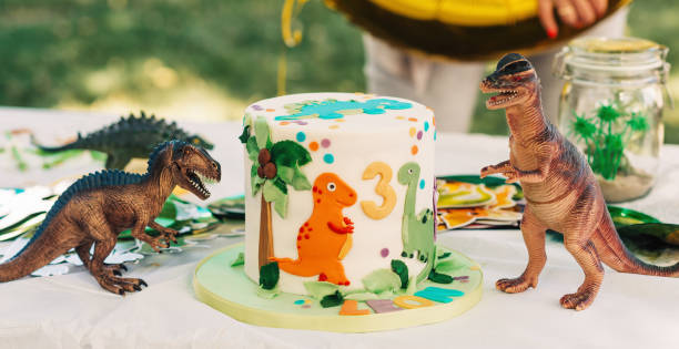 istock Kids birthday party. White mastic cake decorated with dinosaur figurines 1166898646