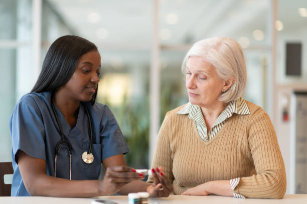 Diabetic senior female patient at medical consultation A senior patient is meeting with her African American female doctor. They are seated together at a table. The patient has diabetes and the doctor is holding an insulin pen. The doctor is explaining how to use the device. low insulin stock pictures, royalty-free photos & images