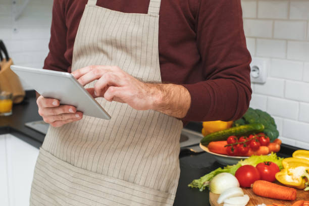 istock Young man cooking romantic dinner at home browsing digital tablet close-up 1166900481