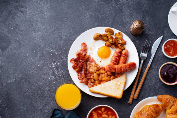 istock Top view flatlay with classical english breakfast with fried bacon, mushrooms and eggs. Served with orange juice, croissants and black coffee. 1166905078