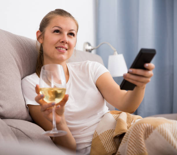 istock Girl is resting with wine and watching TV 1166905800