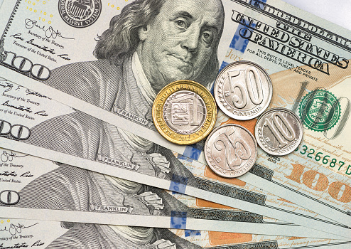 Moneda venezolana encima de billetes de dólar photo