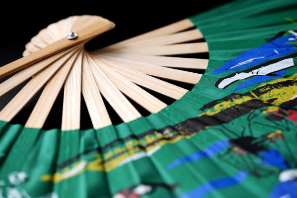 An elegant, slim wooden fan with fine patterns on an orange background.. Flat lay concept.