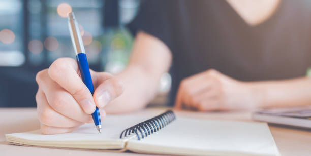 istock Woman hand is writing on a notebook with a pen. 1166932932