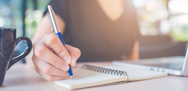 istock Woman hand is writing on a notebook with a pen. 1166932933