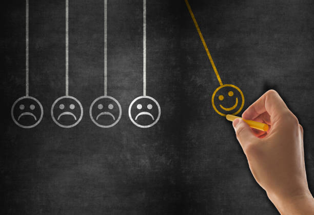 istock Happiness concept with happy and sad faces on newton’s cradle on blackboard 1166938490