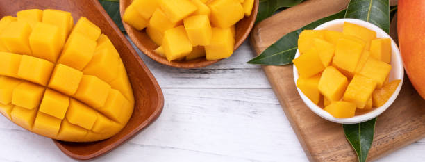 istock Fresh chopped mango on a tray and bright rustic wooden background. Tropical summer fruit design concept. 1166940754