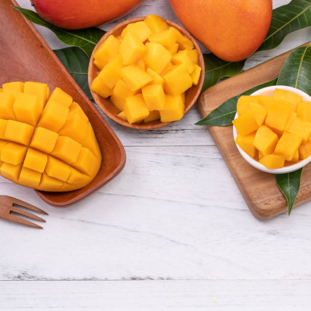 istock Fresh chopped mango on a tray and bright rustic wooden background. Tropical summer fruit design concept. 1166940776