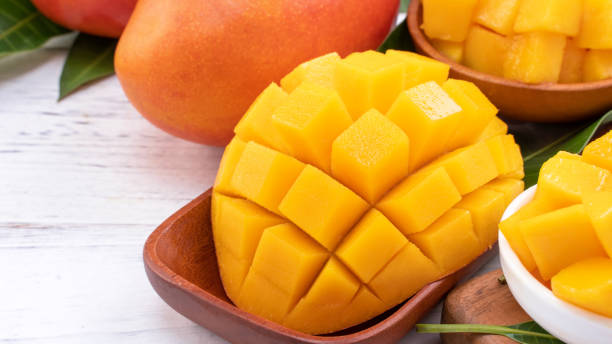 istock Fresh chopped mango on a tray and bright rustic wooden background. Tropical summer fruit design concept. 1166940870