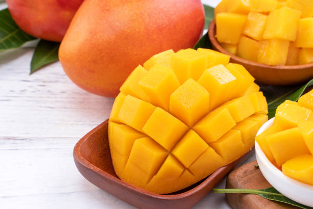 istock Fresh chopped mango on a tray and bright rustic wooden background. Tropical summer fruit design concept. 1166940956