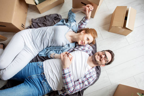 istock Young couple lying at the floor in empty room with unpacked boxes all arround 1166941650