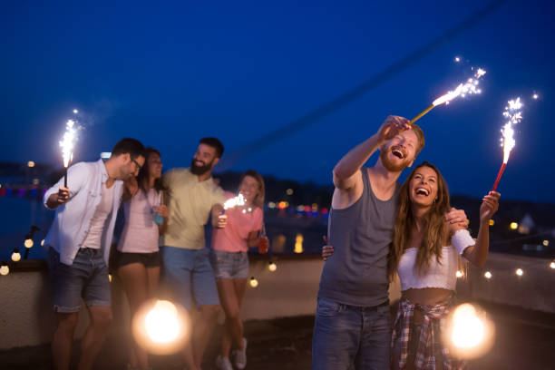 istock Friends enjoying a rooftop party and dancing with sparklers 1166941887