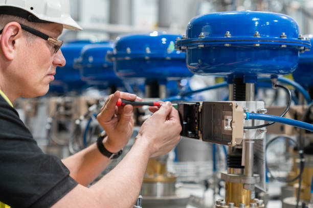 ein servicetechniker prüft ein pneumatisches ventil mit einem schraubendreher - valve stock-fotos und bilder