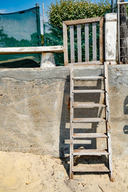 istock Weathered stone wall with ladder and gate from the beach at Arcachon 1166950041