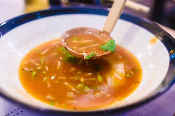 Abstract shallow DOF of pair of black ramen spoon over bottom plate on top of empty wooden table