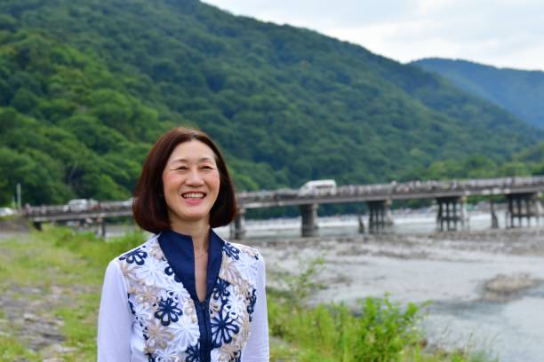 mulher japonesa que anda no beira-rio em arashiyama, kyoto - togetsu kyo bridge - fotografias e filmes do acervo