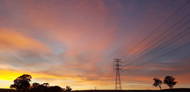 Electricity transmission towers at dawn Rural electricity high voltage wires and transmission poles landscape horizon over land stock pictures, royalty-free photos & images