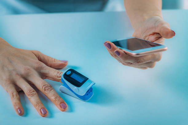 istock Midsection Of Woman Using Mobile Phone And Pulse Oxymeter 1166964992