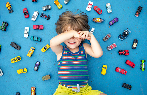 Toddler Lying on Ground, Surrounded by Car Toys