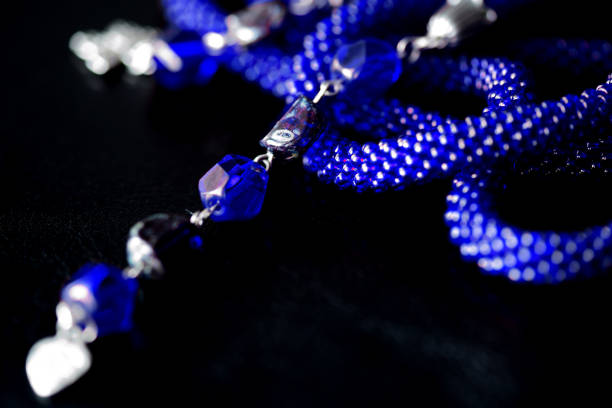 istock Long open necklace (lariat) blue color on a dark background close up 1166980723
