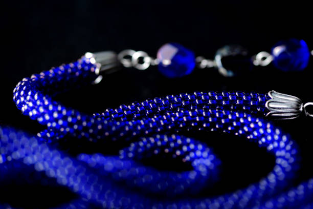 istock Long open necklace (lariat) blue color on a dark background close up 1166980729