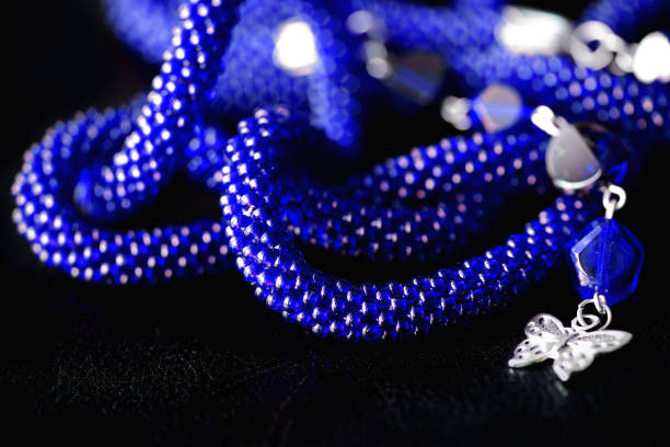 istock Long open necklace (lariat) blue color on a dark background close up 1166980762