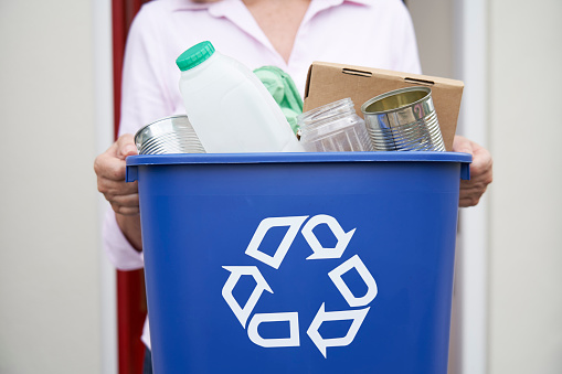 Close Up Of Woman Holding Recycling Bin Of Reusable Waste Outside Front Door