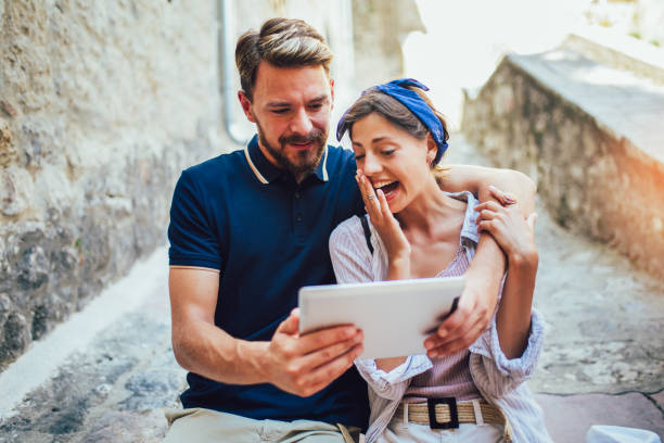 istock Romantic tourist couple sitting on stairs using digital tablet. 1166983576