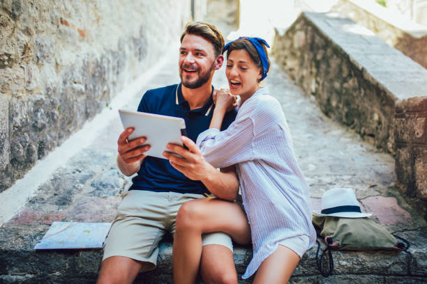 istock Romantic tourist couple sitting on stairs using digital tablet. 1166983578