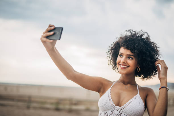 istock Stunning woman taking a selfie on the beach 1166984504