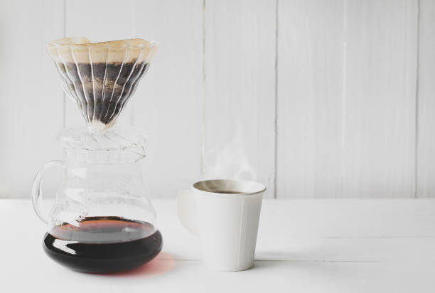 istock Dripping coffee and white paper cup on wood table background 1166985866