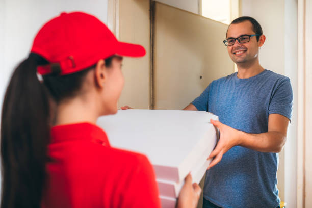 Young Woman Delivering Pizza To man