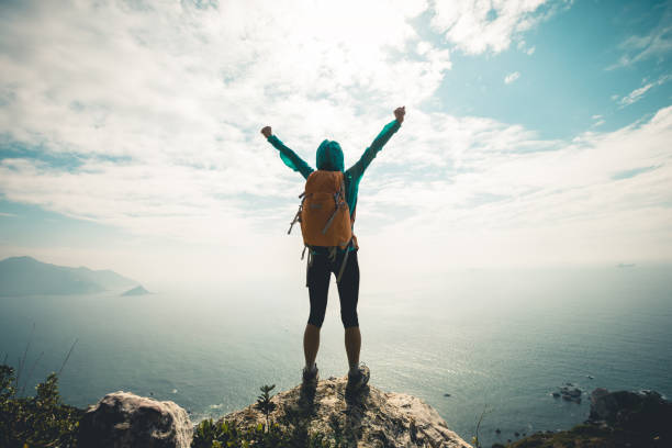 istock Successful hiker outstretched arms at seaside mountain top cliff edge 1166992281