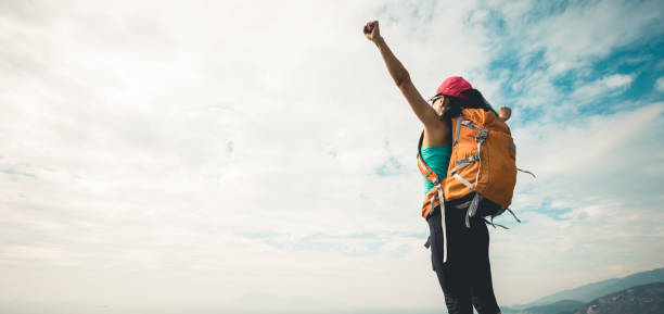 istock Successful hiker outstretched arms at seaside mountain top cliff edge 1166992300