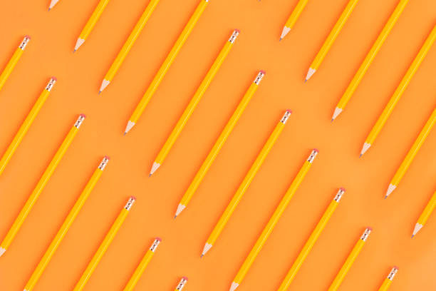 Erasable orange colored wooden pencils diagonal flat lay on orange background