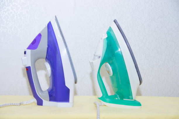 istock Two irons on an ironing board. Selection and comparison of irons. Ironing board. 1166994701