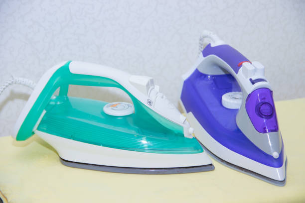 istock Two irons on an ironing board. Selection and comparison of irons. Ironing board. 1166994737