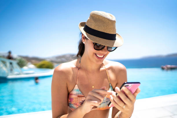 istock Young Woman Using Smartphone In Front Of A Swimming Pool 1166997184