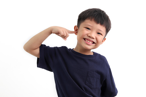 Portrait of cute little asian boy pointing his ear, isolated on white background