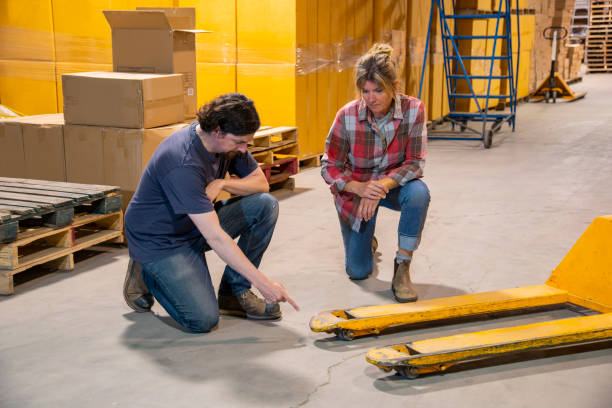 istock An industrial warehouse workplace safety topic.  A worker points out a damaged pallet jack to a coworker or supervisor. 1166997889
