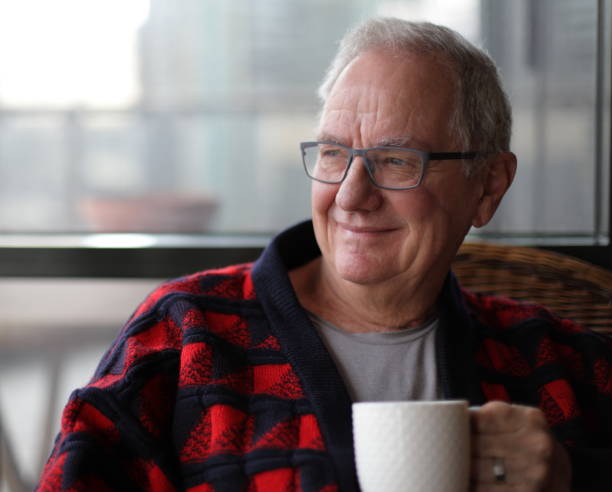 istock Smiling senior man with coffee by the window 1166998133